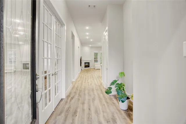 a view of a hallway with wooden floor and a bathroom