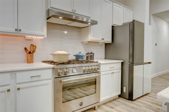 a kitchen with stainless steel appliances white cabinets and a refrigerator