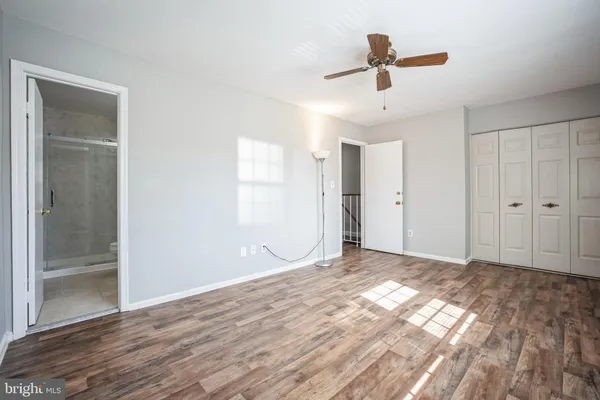 a view of empty room with wooden floor and fan