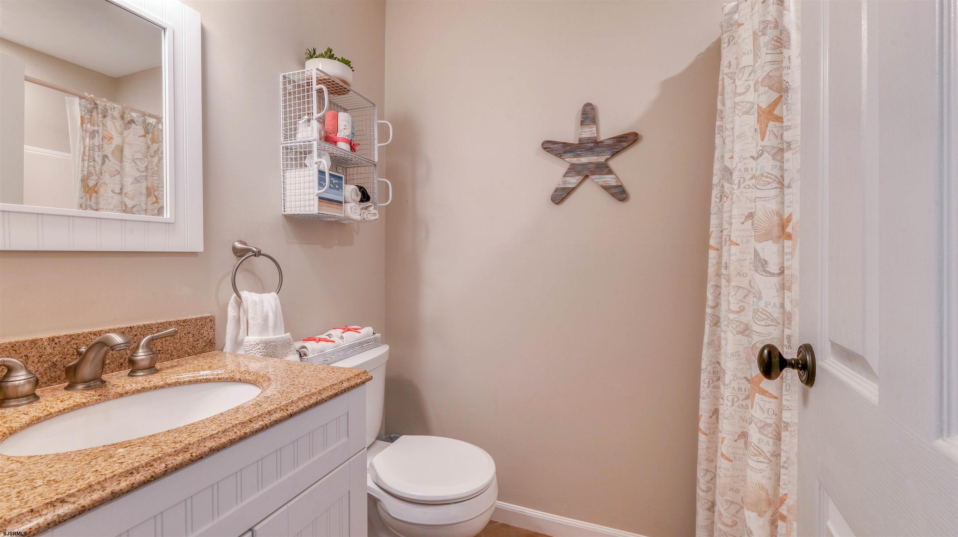 525 Lagoon Boulevard Brigantine, NJ 08203 - Photo 26 of 52 a bathroom with a granite countertop sink toilet and a mirror