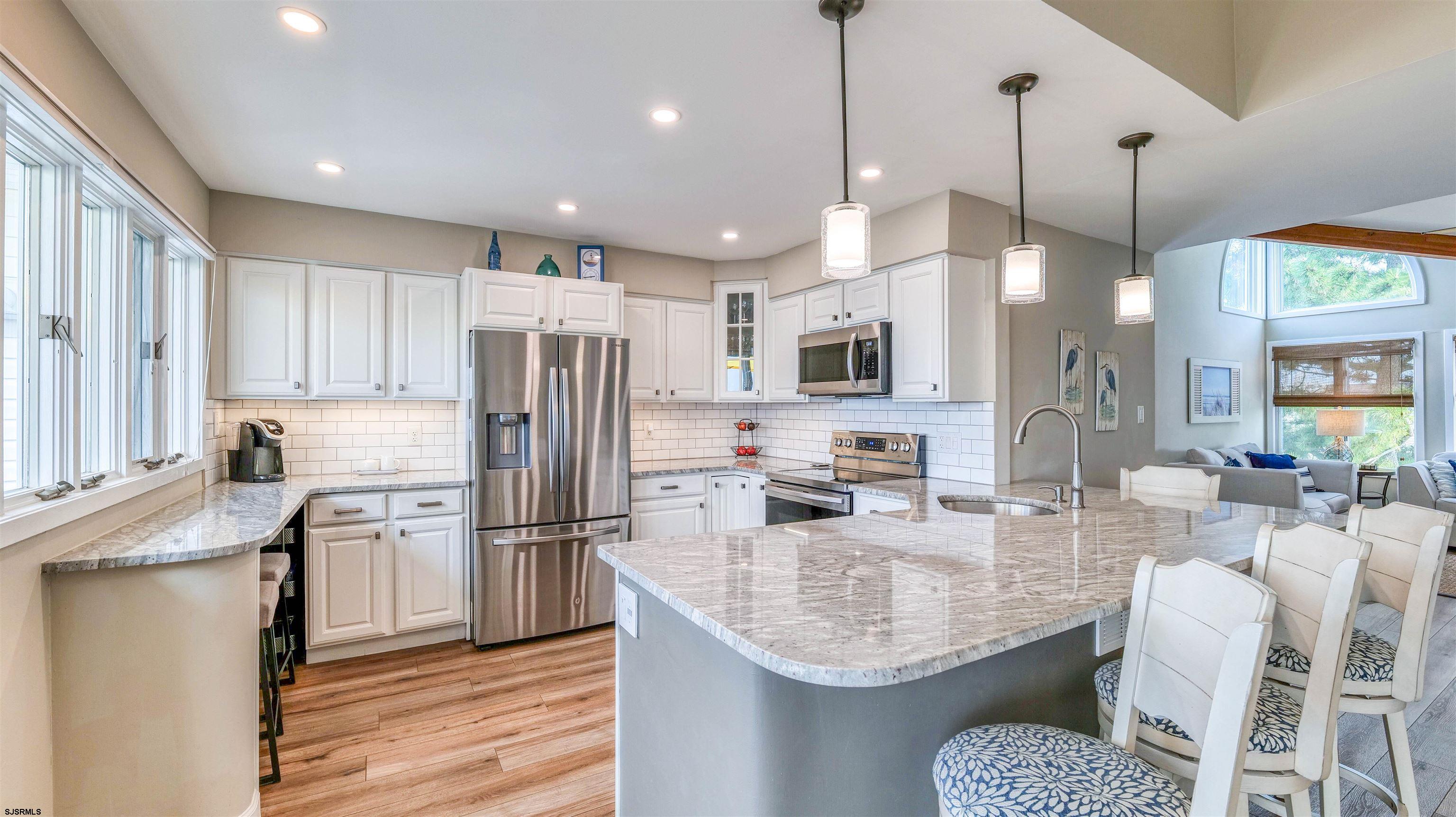 525 Lagoon Boulevard Brigantine, NJ 08203 - Photo 42 of 52 a kitchen with stainless steel appliances granite countertop a refrigerator a oven a sink a island and chairs with wooden floor