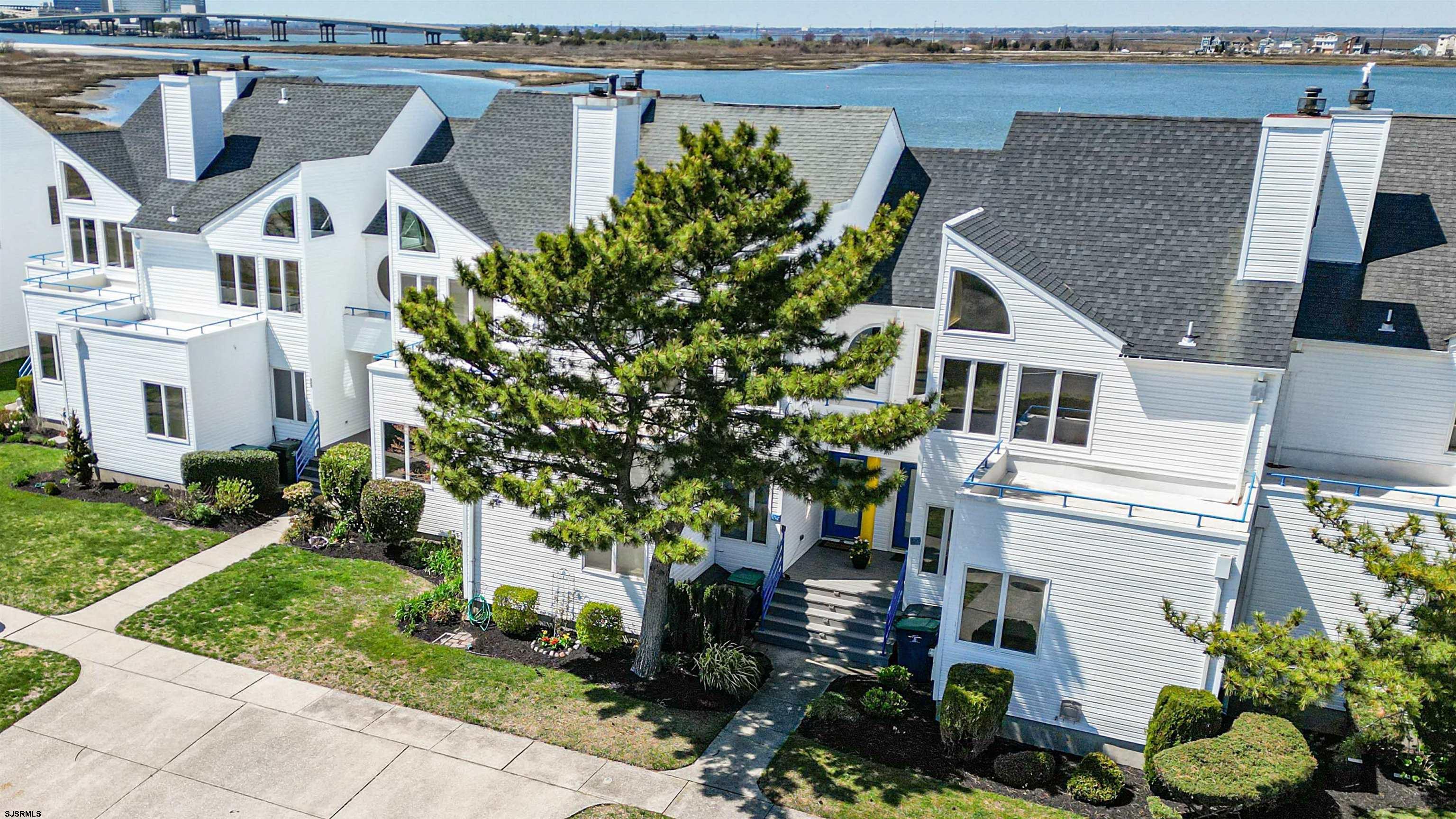 525 Lagoon Boulevard Brigantine, NJ 08203 - Photo 9 of 52 a view of a white house next to a yard with plants and large trees