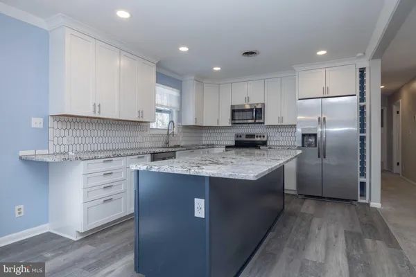 a kitchen with kitchen island granite countertop a sink stove and refrigerator