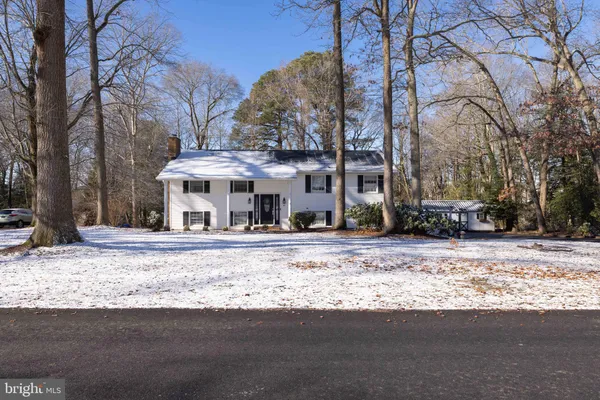 a view of a house with a yard covered with snow and trees