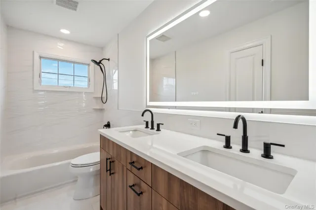 a bathroom with a double vanity sink toilet and a bathtub