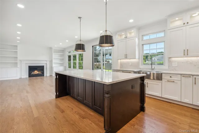 a kitchen with kitchen island granite countertop a stove a sink a center island and wooden floor