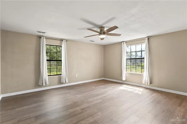 a view of an empty room with a window and wooden floor