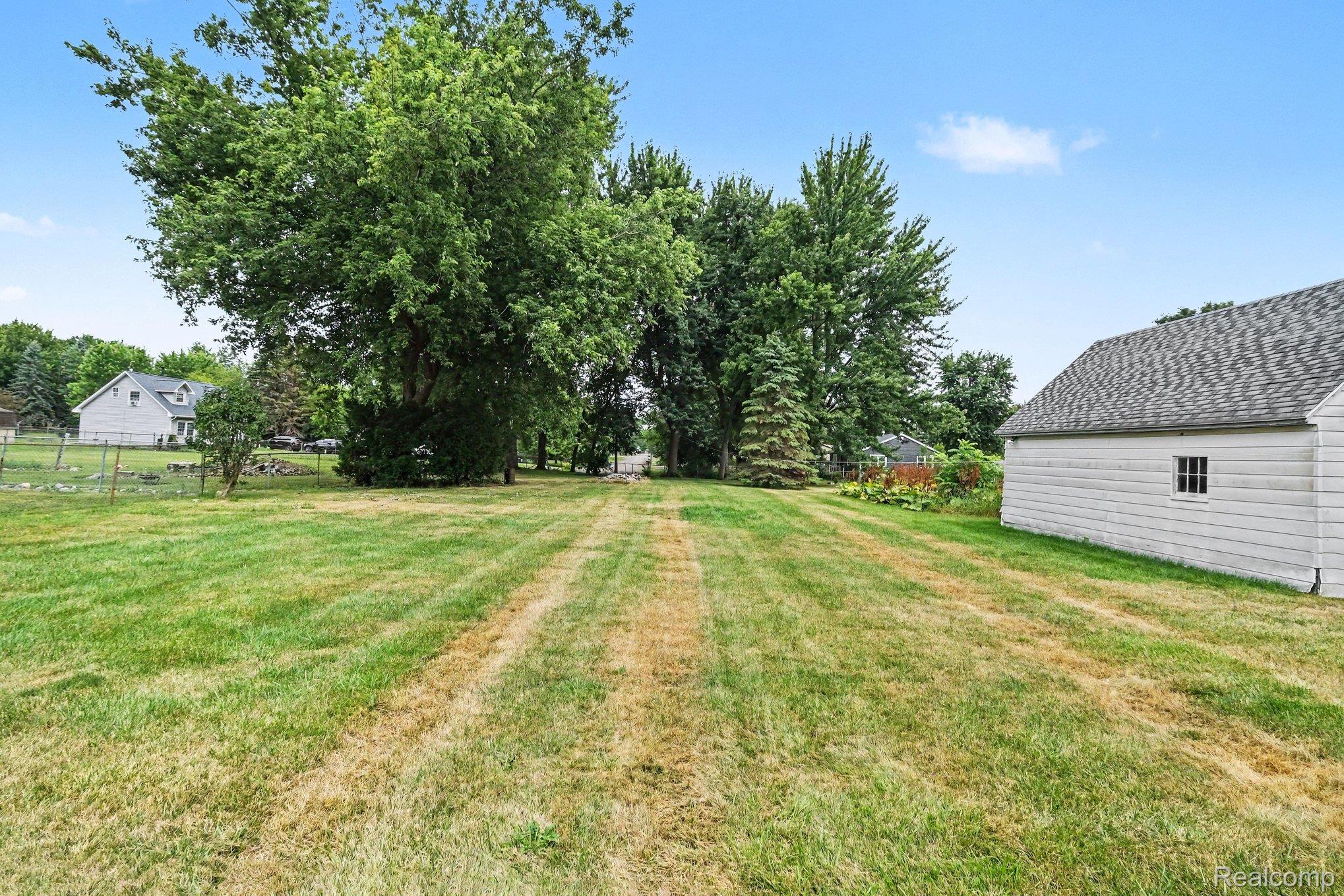 5199 Lapeer Road Burton, MI 48509 - Photo 16 of 19 Expansive rear yard featuring a detached auxiliary building with white siding and an asphalt shingle roof