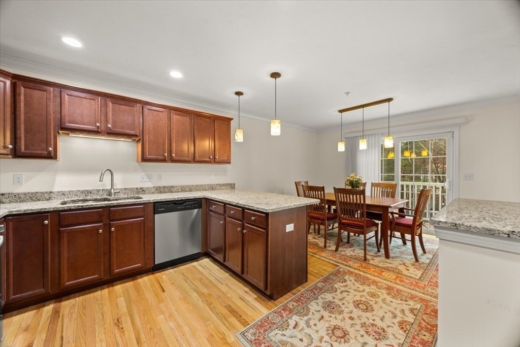 22 Highland Road, Unit 29 Raynham, MA 02767 - Photo 15 of 36 a kitchen with stainless steel appliances granite countertop a stove top oven a sink dishwasher a dining table and chairs with wooden floor