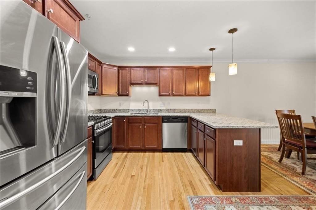22 Highland Road, Unit 29 Raynham, MA 02767 - Photo 18 of 36 a kitchen with stainless steel appliances granite countertop a refrigerator a sink dishwasher a stove with wooden floor