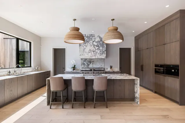 a large kitchen with stainless steel appliances a stove a sink dishwasher and a refrigerator with wooden floor