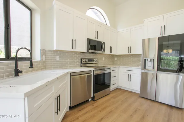 a kitchen with granite countertop a sink stainless steel appliances and white cabinets