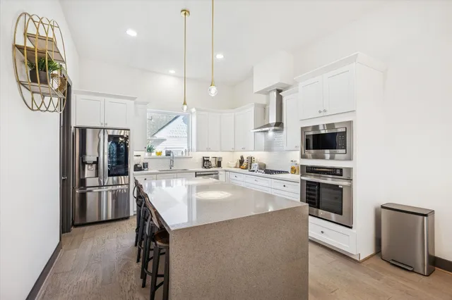 a kitchen with stainless steel appliances granite countertop a stove a refrigerator a oven a sink a dining table and chairs with wooden floor