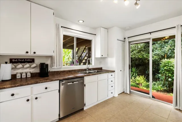 a kitchen with stainless steel appliances granite countertop white cabinets and a window