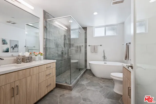 a bathroom with a granite countertop sink a toilet a mirror and shower