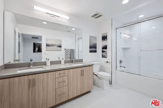 a bathroom with a double vanity sink toilet mirror and bathtub
