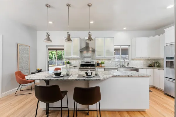 a kitchen with stainless steel appliances kitchen island granite countertop a sink a stove a dining table and chairs