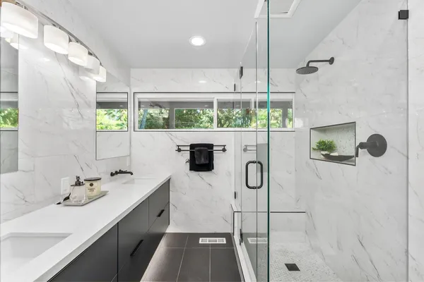 a bathroom with a double vanity sink a mirror and shower