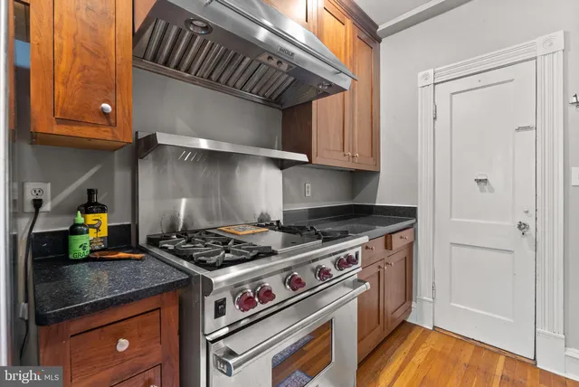 a kitchen with granite countertop a stove and a wooden cabinets