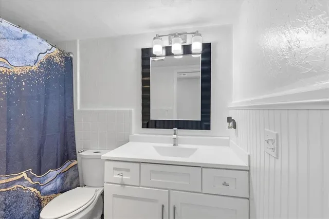 a bathroom with a sink vanity mirror and toilet