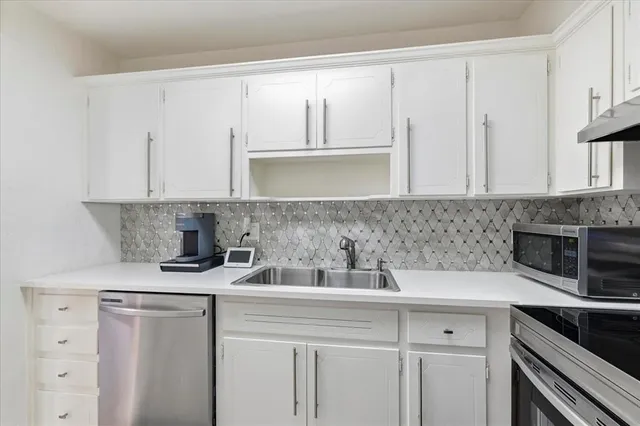 a kitchen with white cabinets and white appliances