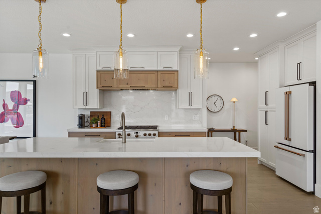 3349 Oxford Loop Morgan, UT 84050 - Photo 5 of 47 Kitchen with a kitchen breakfast bar, dual tone cabinets, white appliances, tasteful backsplash, and light wood-type flooring