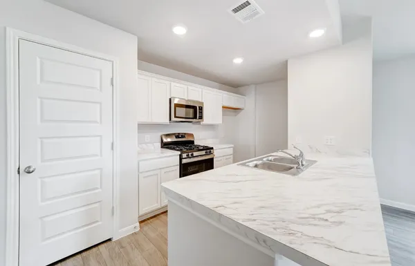 a kitchen with a refrigerator a stove and white cabinets