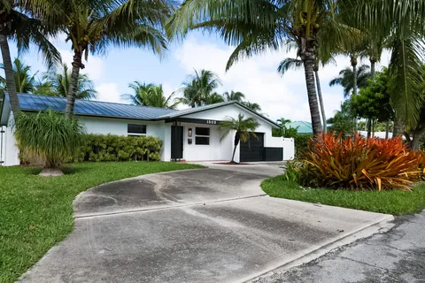front view of a house with a yard and palm trees