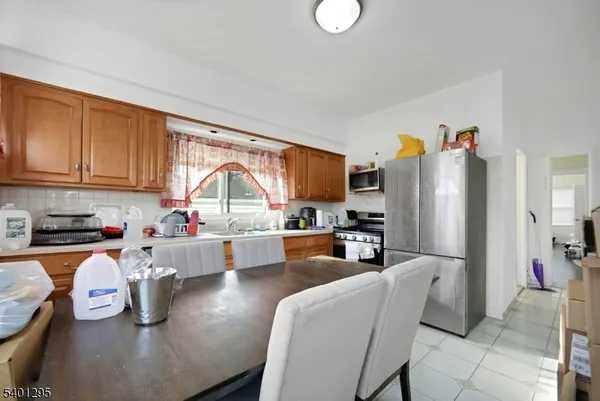 a kitchen with stainless steel appliances granite countertop a refrigerator a sink dishwasher a dining table and chairs with wooden floor