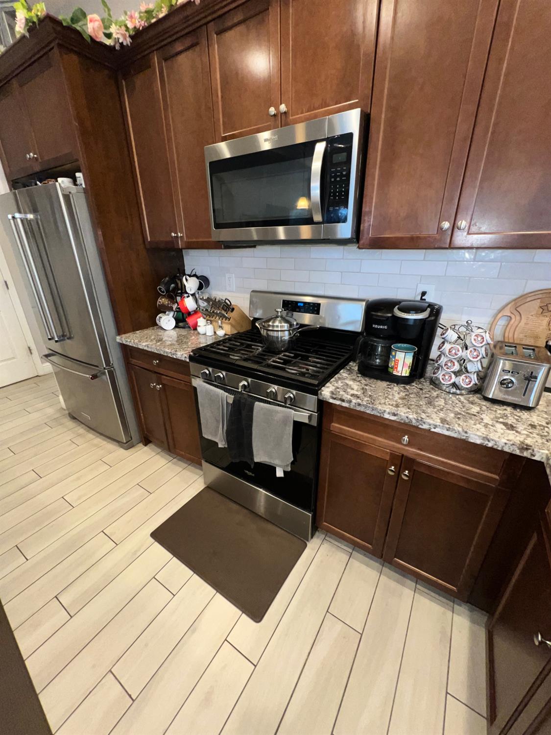 889 Coloma Place Madera, CA 93637 - Photo 16 of 61 a kitchen with stainless steel appliances kitchen island granite countertop a stove a sink and a microwave
