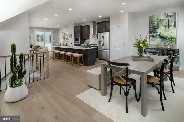 a kitchen with stainless steel appliances kitchen island granite countertop a table chairs and a living room