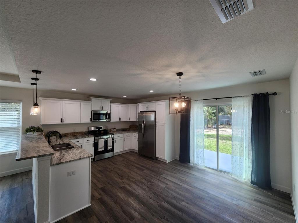820 Redwood Road Dunnellon, FL 34431 - Photo 6 of 28 a kitchen with stainless steel appliances granite countertop a refrigerator a stove a sink dishwasher and a refrigerator with wooden floor