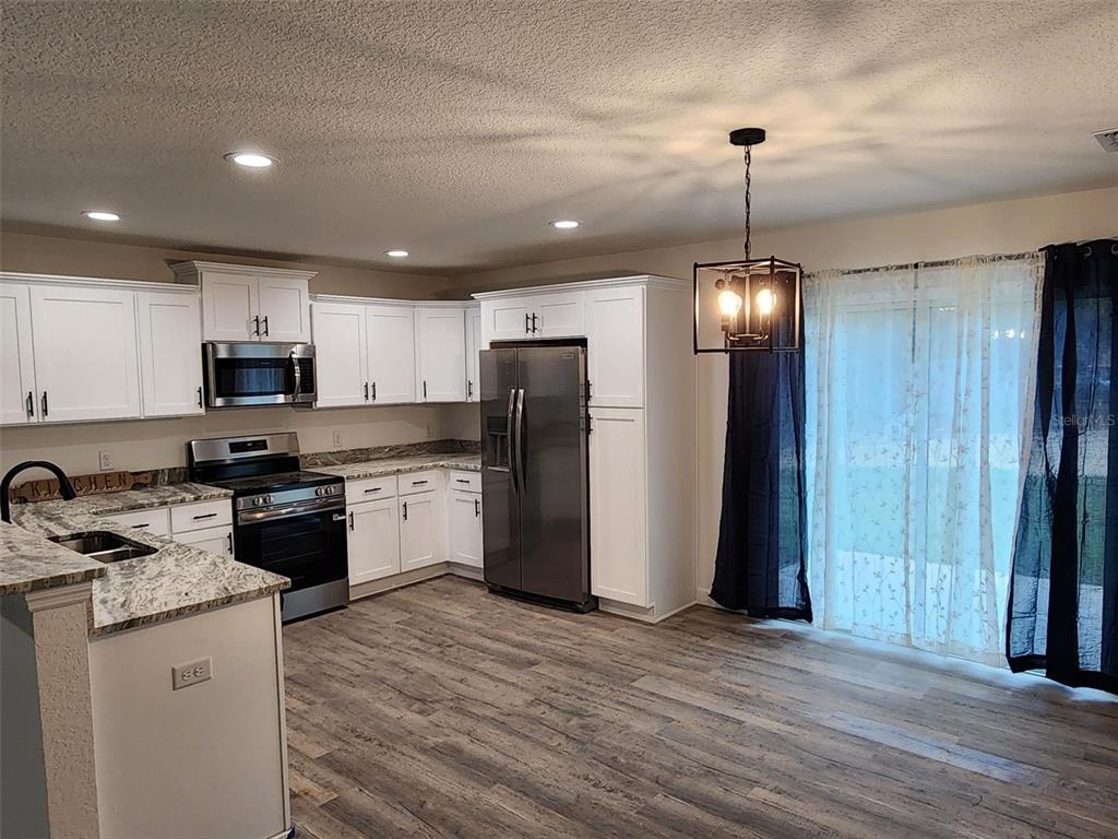 820 Redwood Road Dunnellon, FL 34431 - Photo 7 of 28 a kitchen with stainless steel appliances granite countertop a refrigerator a sink dishwasher a stove and a kitchen island