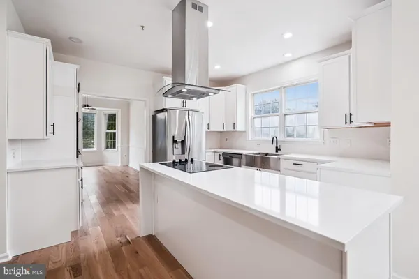 a large white kitchen with kitchen island a stove a sink a refrigerator and cabinets