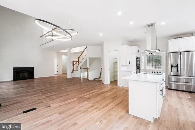 a large kitchen with stainless steel appliances kitchen island a stove a refrigerator a oven and a wooden floors