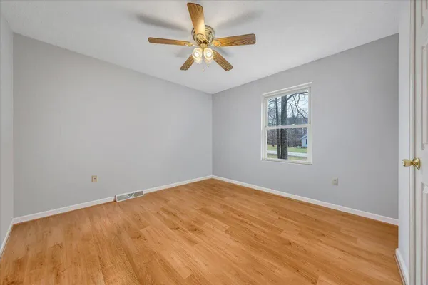 an empty room with a window and a fan