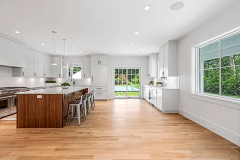 a kitchen with stainless steel appliances granite countertop a stove top oven a sink dishwasher a dining table and chairs with wooden floor