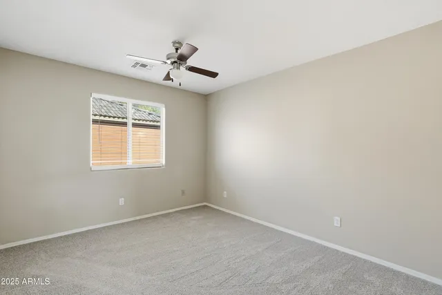 an empty room with a window and a fan