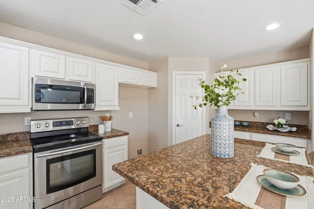 a kitchen with stainless steel appliances kitchen island granite countertop a sink dishwasher stove and microwave with wooden floor