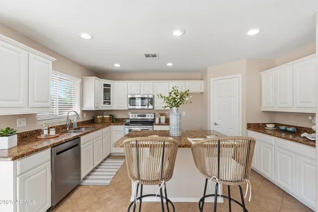 a kitchen with stainless steel appliances kitchen island granite countertop a sink and cabinets