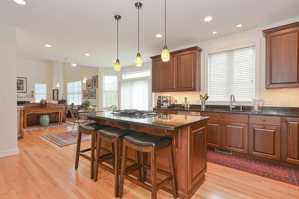 1 Ridgewood Street Ashland, MA 01721 - Photo 7 of 30 a kitchen with stainless steel appliances granite countertop wooden cabinets a stove a sink a dining table and chairs