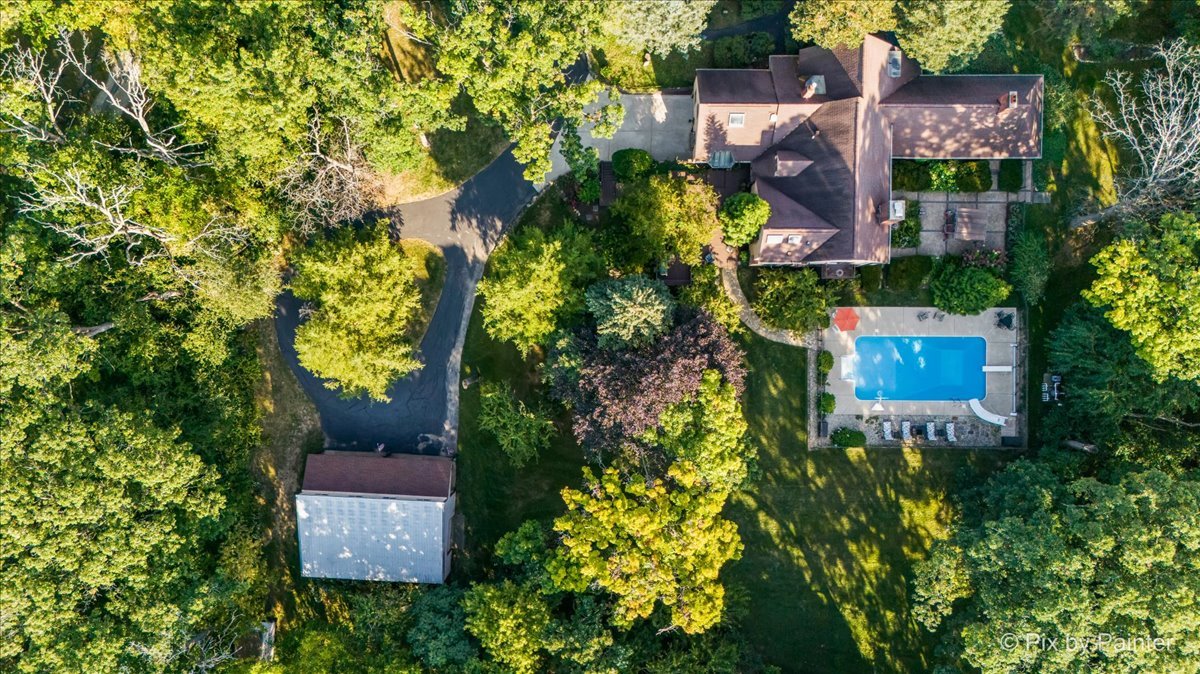 aerial view of a house with a yard and large trees