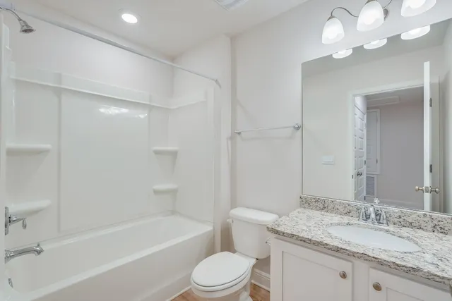 a bathroom with a granite countertop sink a toilet and bathtub