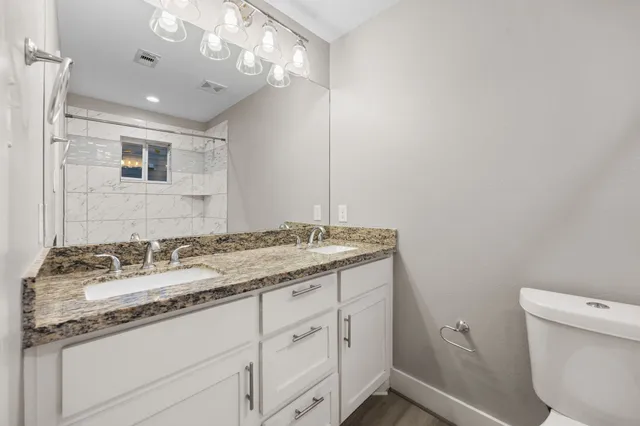 a bathroom with a granite countertop sink a large mirror and a toilet