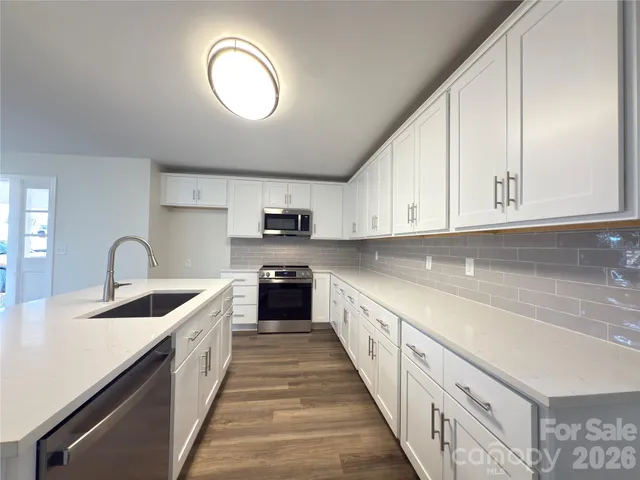 a large kitchen with stainless steel appliances granite countertop a sink and cabinets