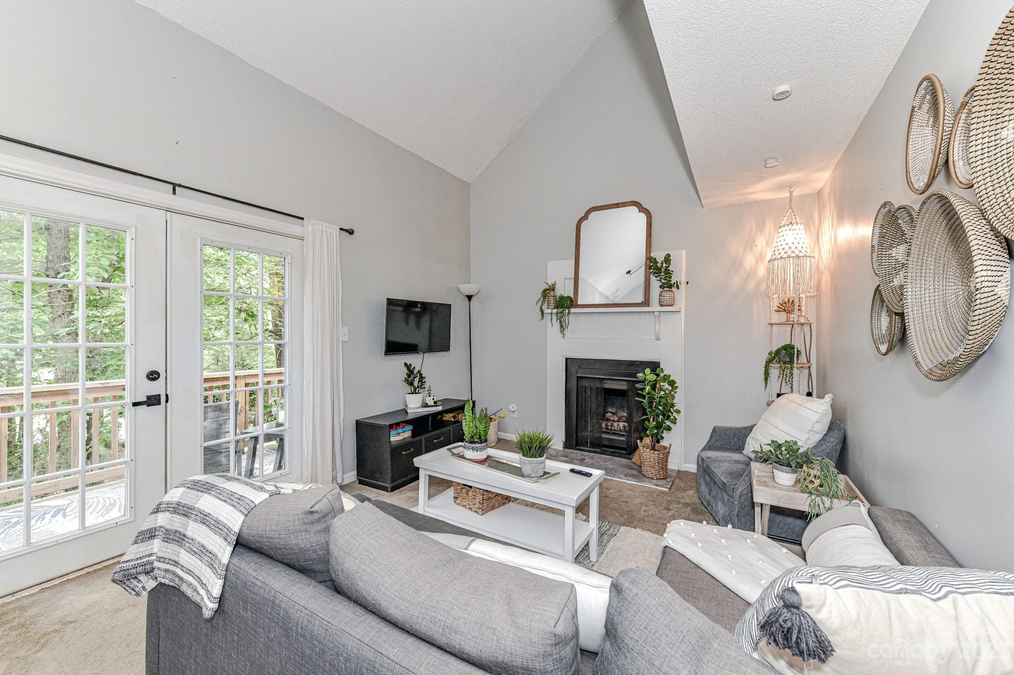 27046 Tidal Way Tega Cay, SC 29708 - Photo 4 of 20 a living room with furniture a fireplace and a large window