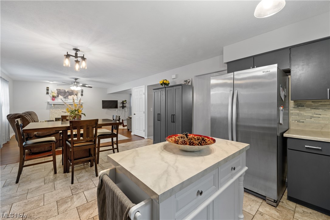 1110 Spring Road Cleveland, OH 44109 - Photo 12 of 33 Kitchen with light tile floors, a kitchen island, stainless steel fridge, tasteful backsplash, and ceiling fan with notable chandelier