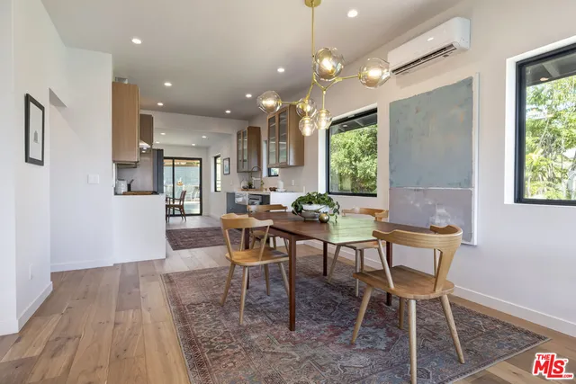 a large kitchen with stainless steel appliances granite countertop a stove oven a sink dishwasher a dining table and chairs with wooden floor