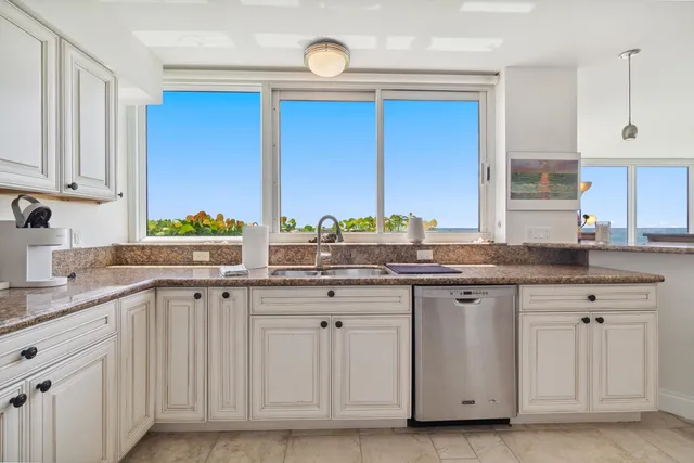 a kitchen with stainless steel appliances granite countertop a sink and dishwasher with white cabinets