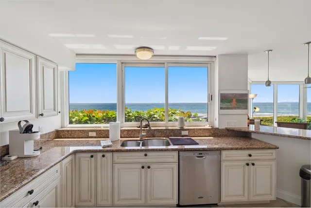 a kitchen with kitchen island granite countertop a sink and a large window